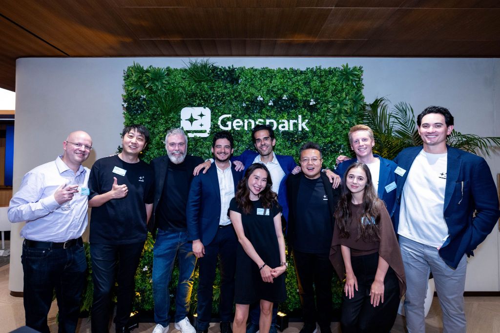 The Genspark team standing together in front of a Genspark living-wall logo